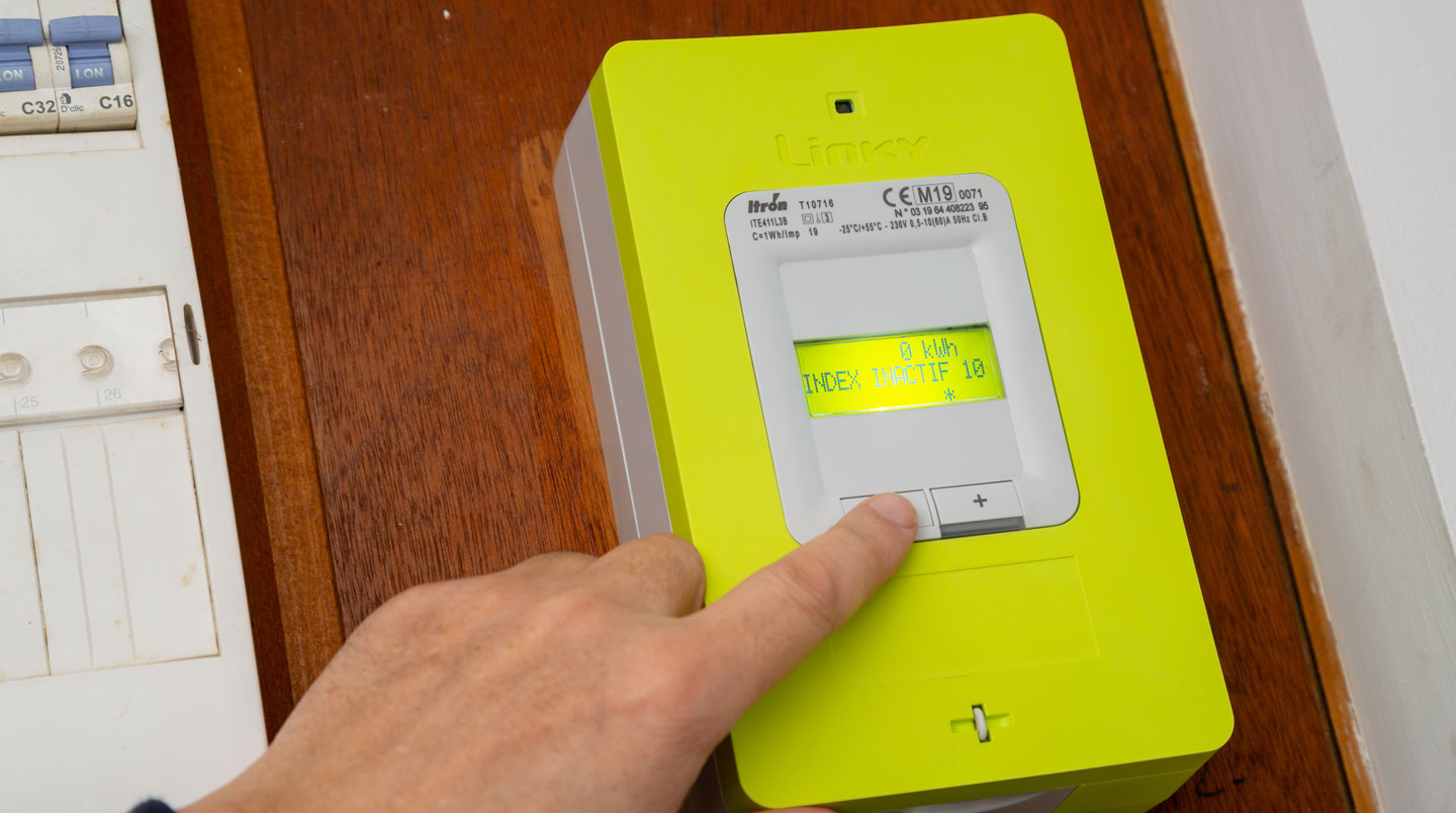 Artisan électricien vérifiant un compteur Linky dans un local professionnel